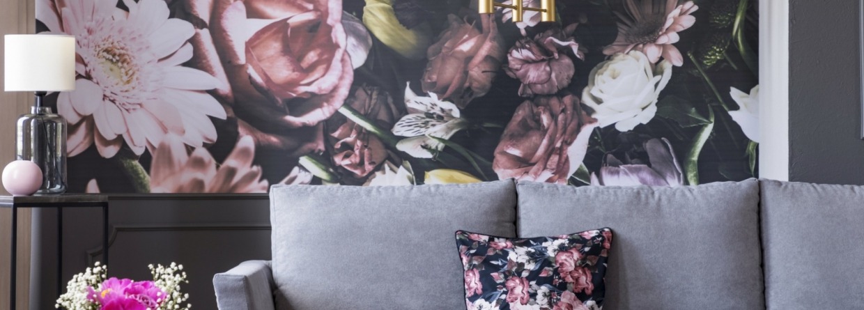 Fotobehang met bloemen achter grijze bank