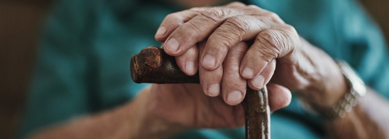 senior leunend met handen op wandelstok
